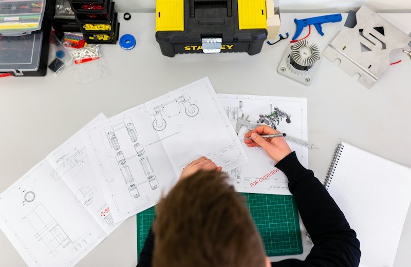 Trainee working on technical drawings at a workshop desk