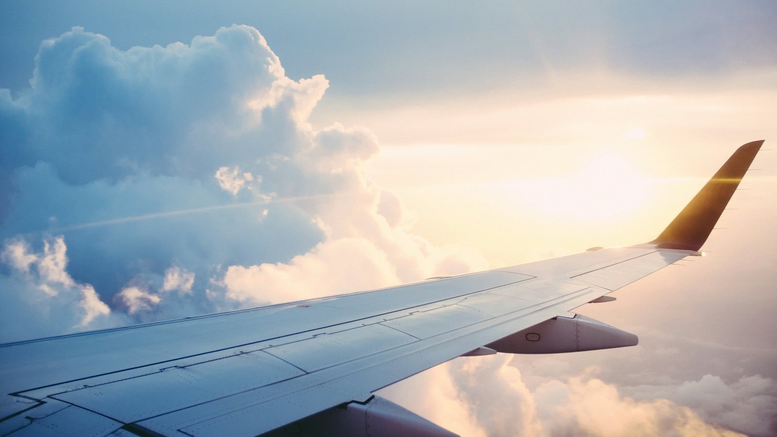 Aircraft wing above the clouds at sunrise, symbolising international travel