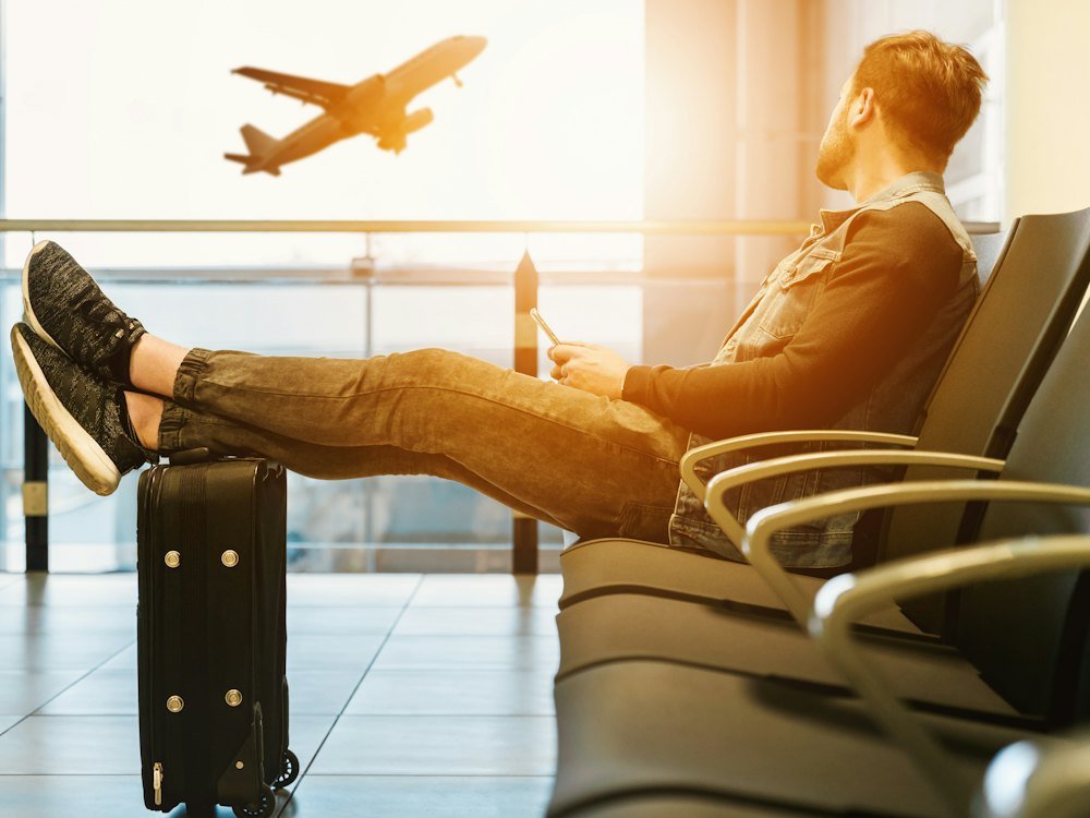Traveller relaxing in an airport lounge as a plane takes off outside