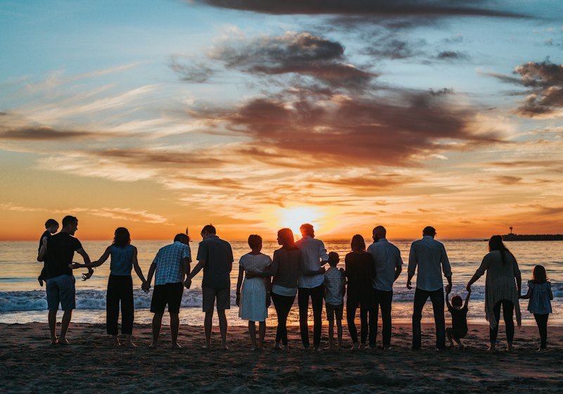 Family holding hands on a beach at sunset